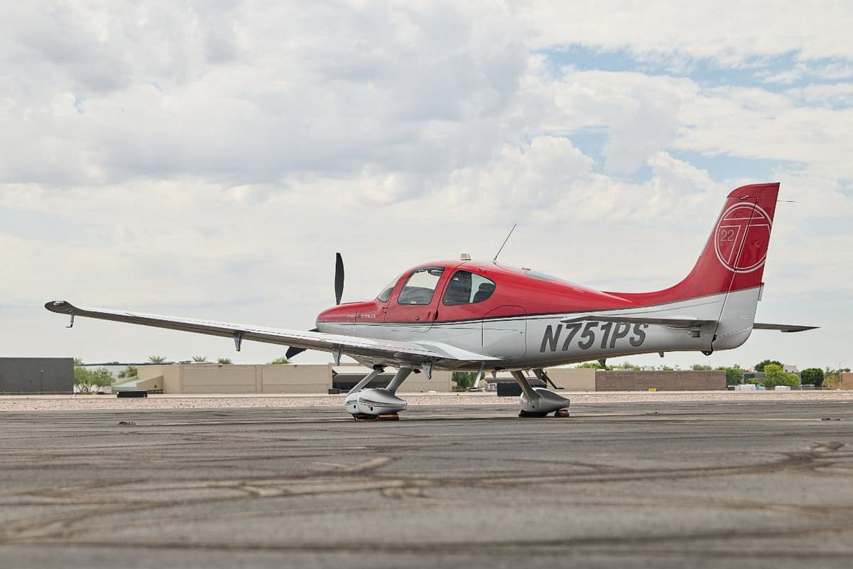 Cirrus SR22T aircraft with a red and silver paint scheme on the tarmac.