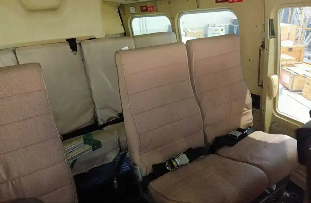 The interior cabin of a helicopter with rows of tan fabric seats.
