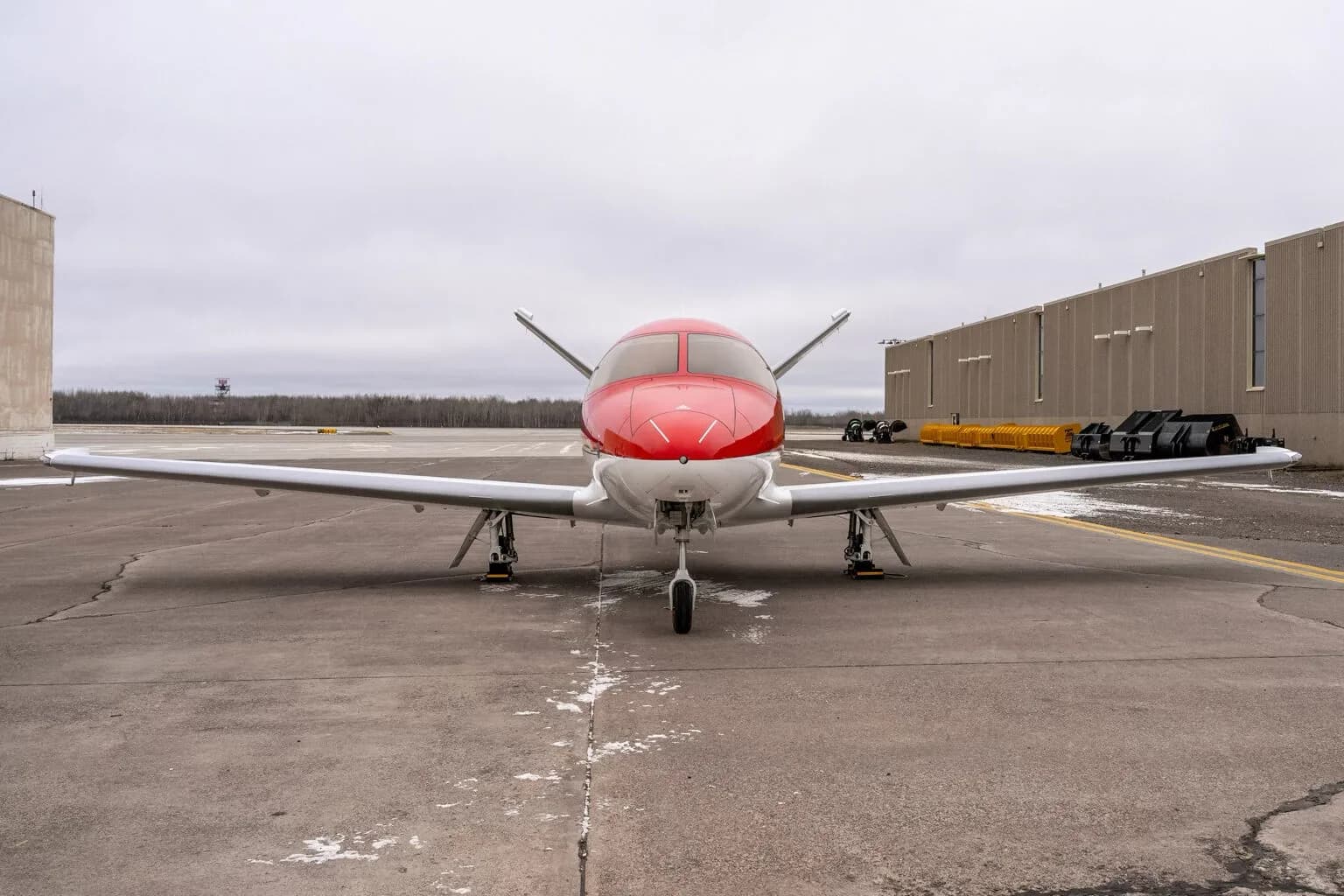 Front view of a red and white Cirrus Vision Jet on the tarmac.