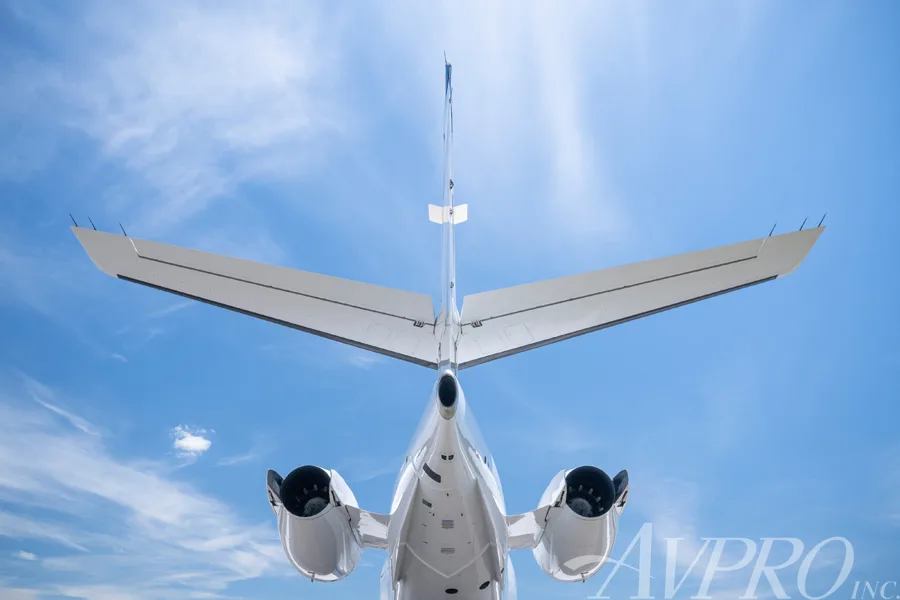 A rear view of the Gulfstream G200 business jet, showing its T-tail and engines against a blue sky.