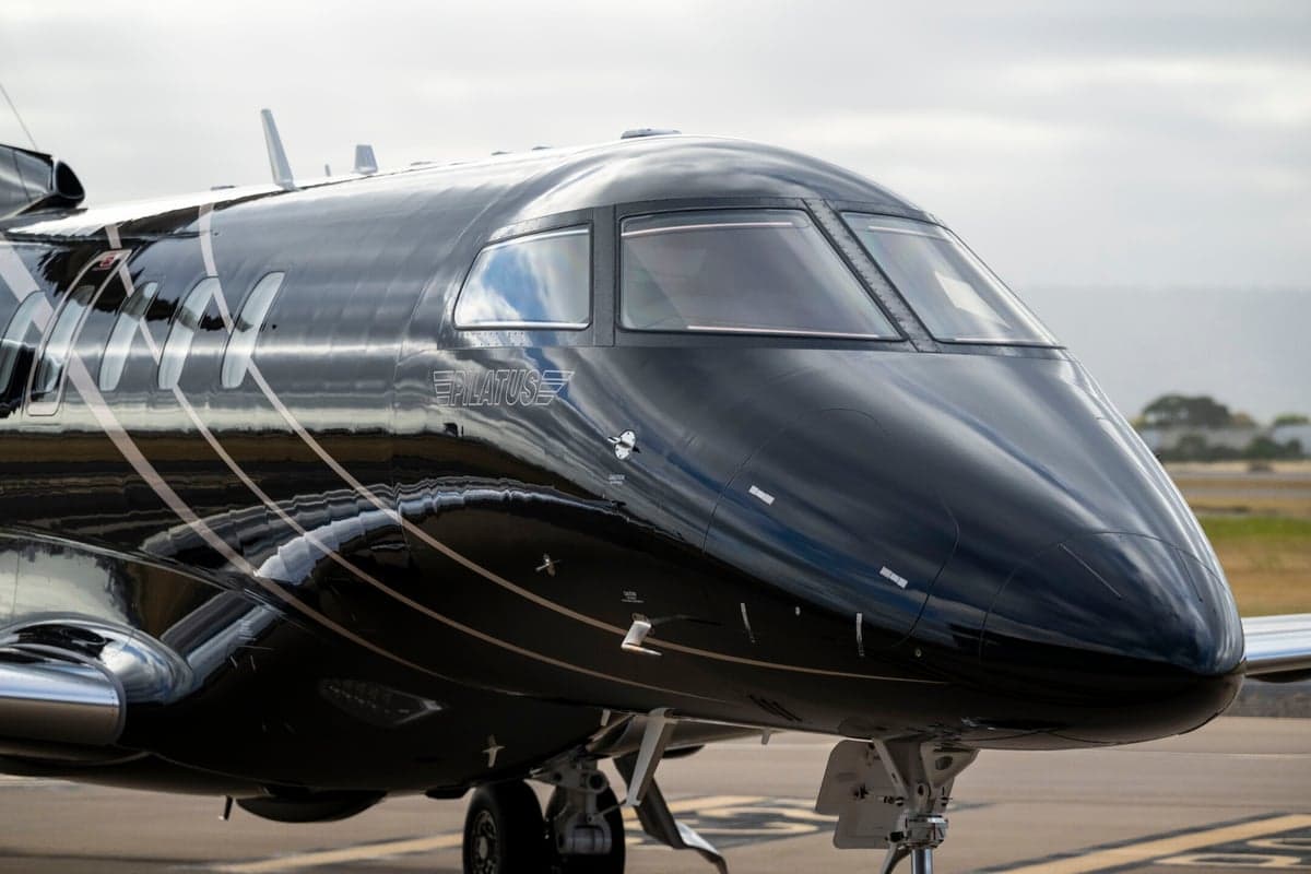 Close-up of the cockpit and nose of a black Pilatus PC-24 jet.