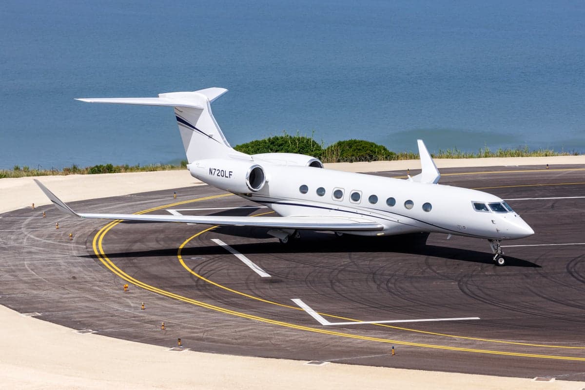 A white Gulfstream jet with registration N720LF parked on a runway near the ocean.