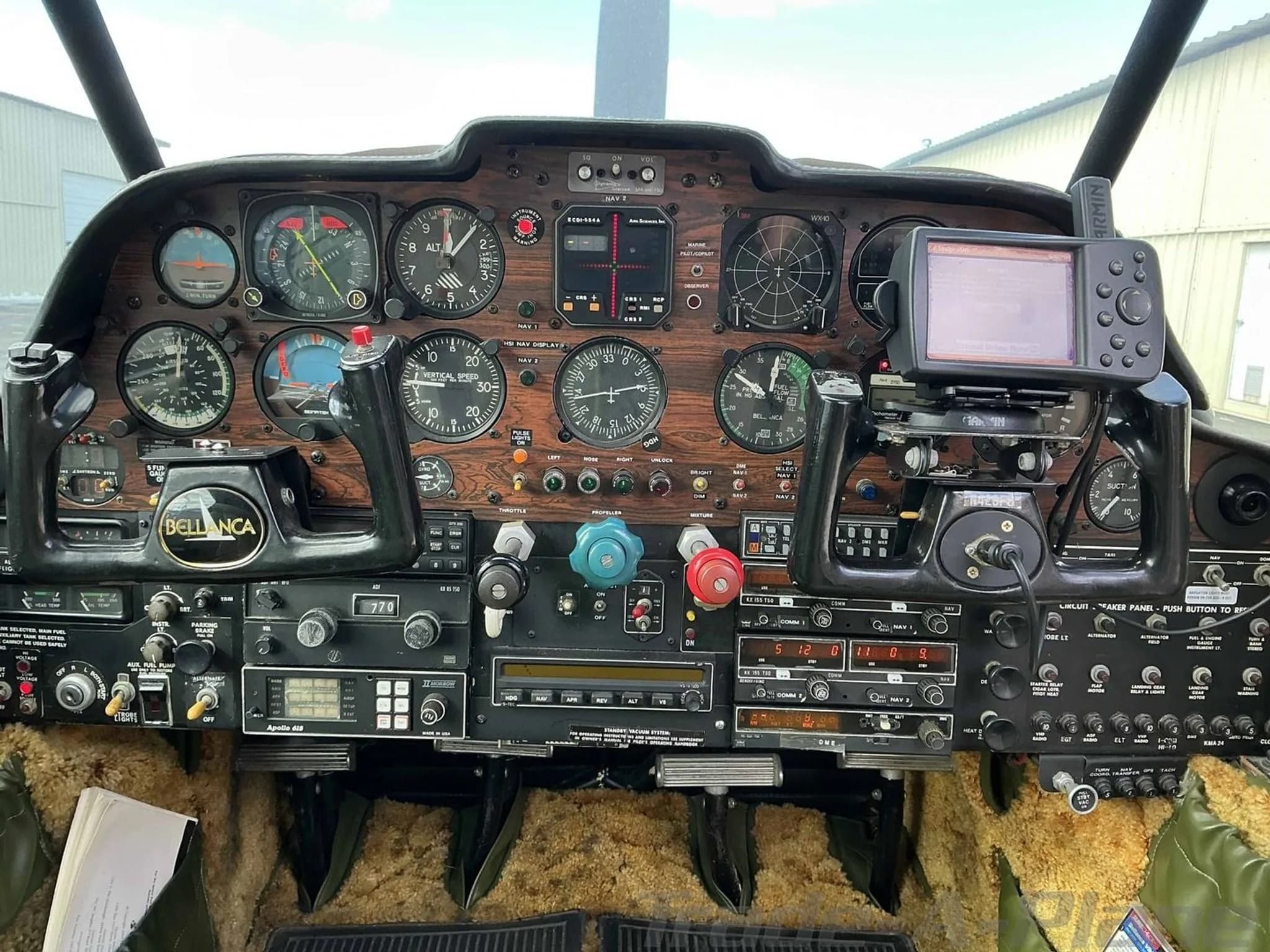 A wide view of the Bellanca Viking's cockpit instrument panel, featuring a woodgrain finish and a GPS unit mounted on the right.