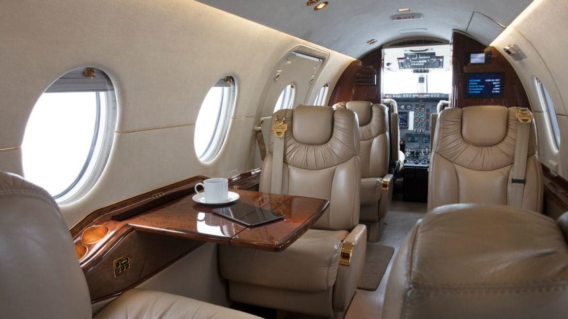View of the aircraft's interior, showing the seating arrangement and table with a cup of coffee and tablet.