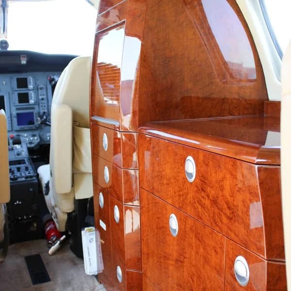 Detailed view of the polished wood cabinetry inside the aircraft cabin, with the cockpit visible in the background.