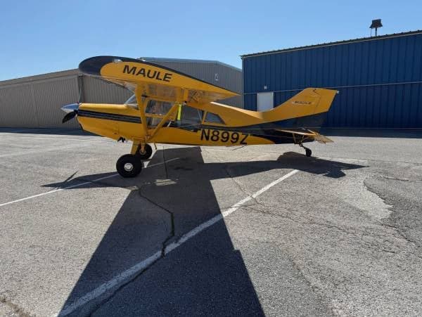 A yellow and blue Maule M-7-235 aircraft with registration N899Z parked on the tarmac.