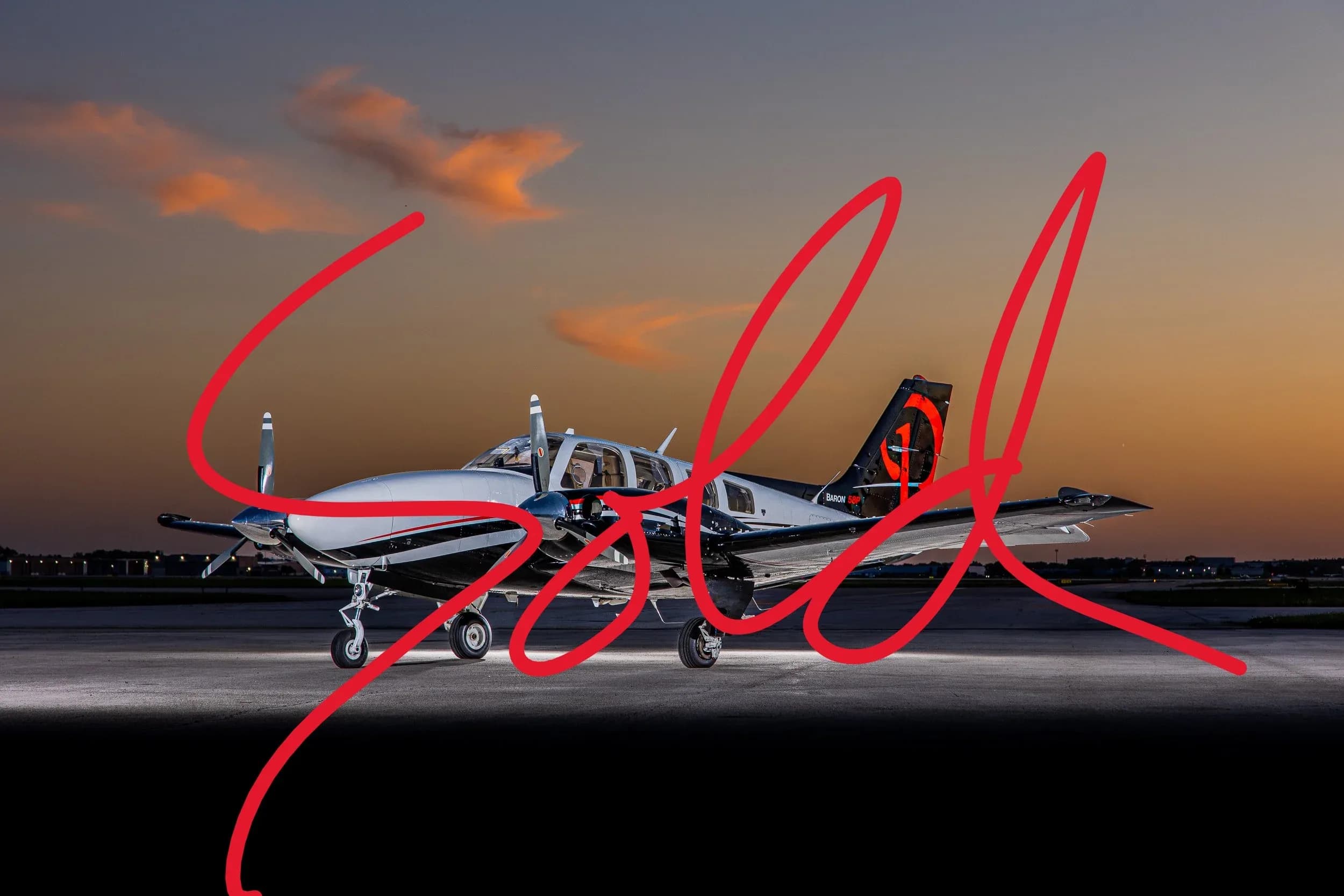 A twin-engine piston aircraft with a black and white paint scheme, parked on an airfield at sunset.