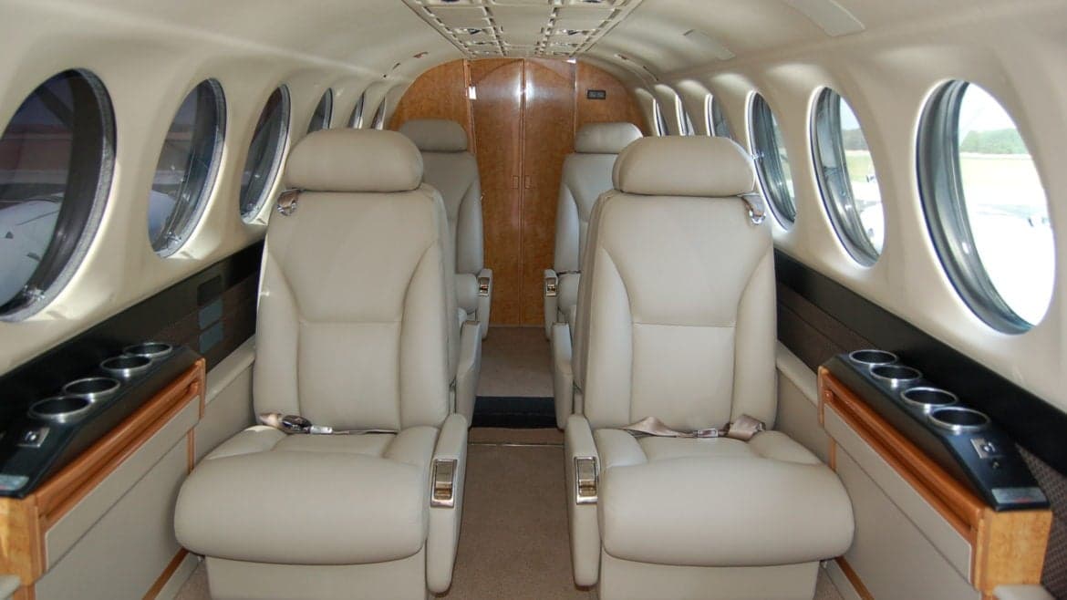 Wide view of the aircraft's cabin with leather seats and oval windows.