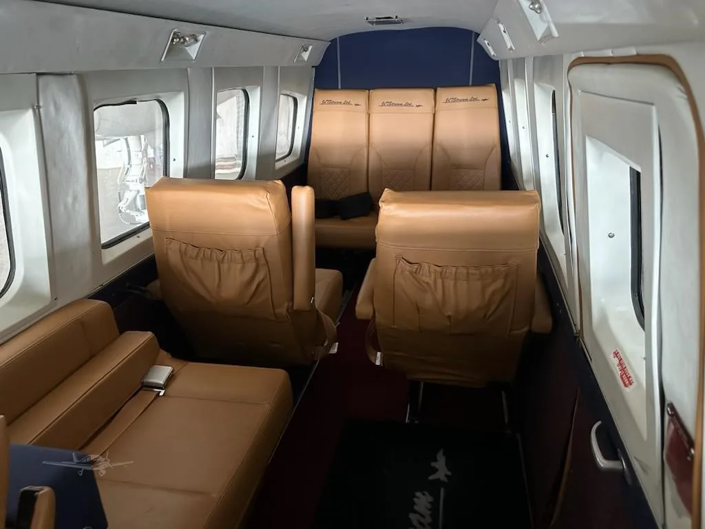 The aircraft's cabin interior with multiple rows of tan leather seats and windows along the side.