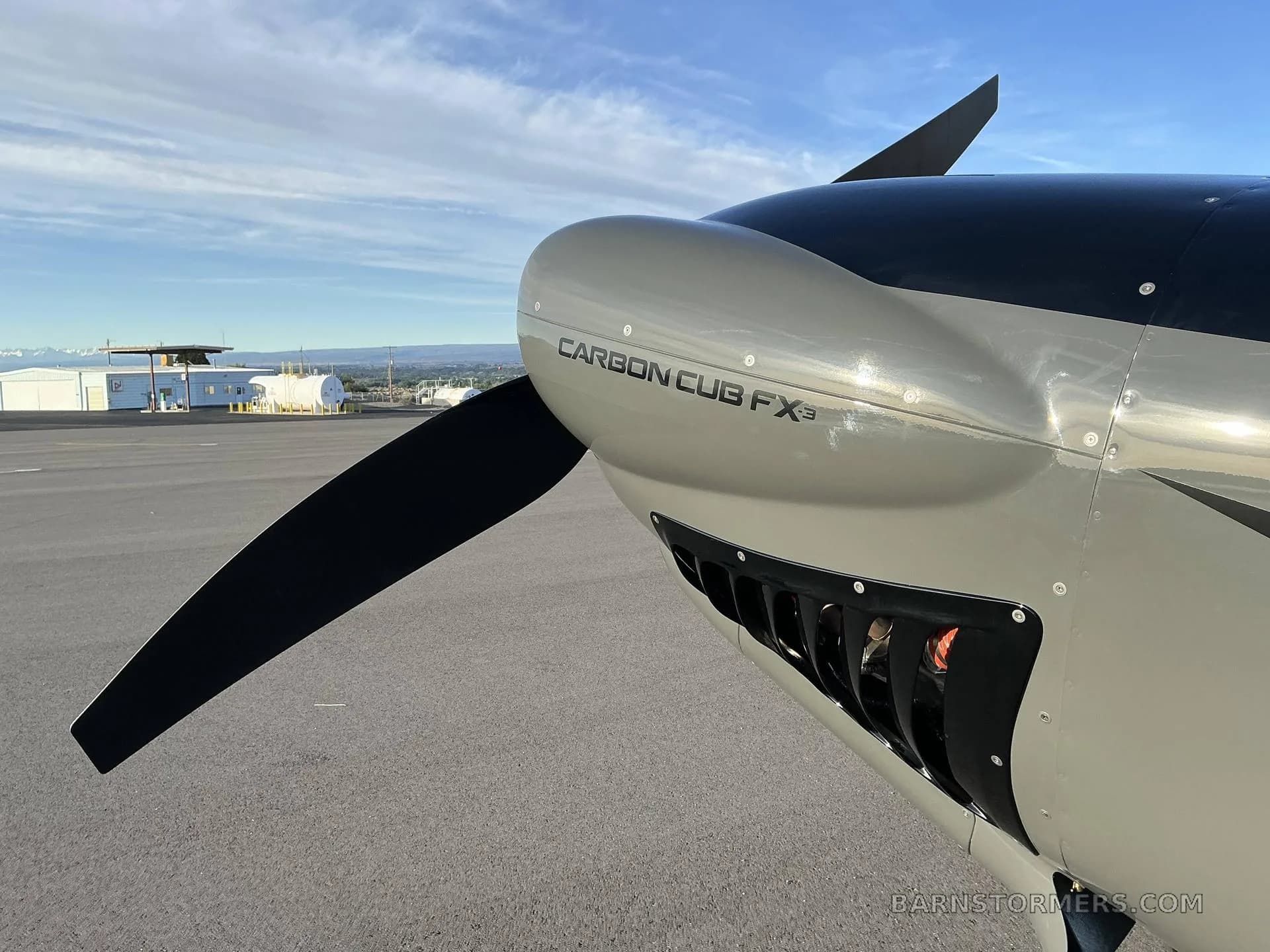 A close-up of the propeller and nose of a grey Carbon Cub FX3 aircraft, showing the engine cowling.