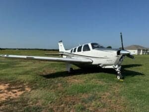 Beechcraft Bonanza N333SM parked on a grassy field.