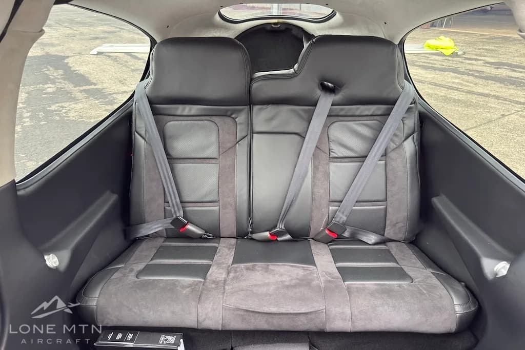A wider view of the black and grey rear passenger seats inside the Cirrus SR22 aircraft.