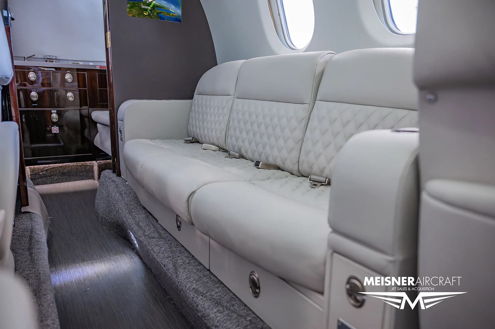 A close-up view of the long, quilted white leather couch in the business jet's cabin.