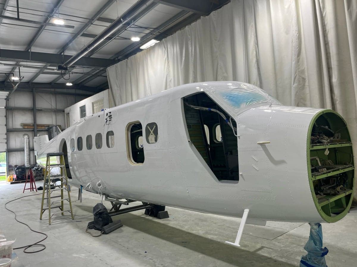 An aircraft fuselage in a hangar, undergoing refurbishment.