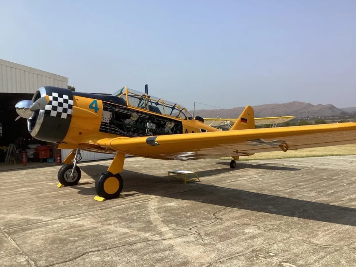 A yellow T-6 Texan aircraft with its engine compartment open.