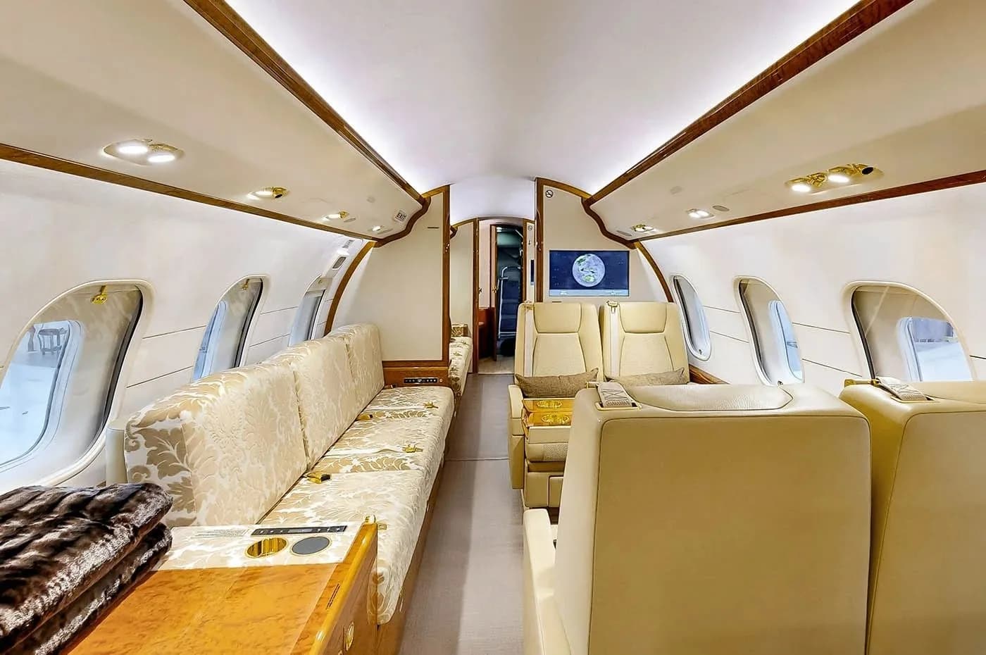 A long view of the aircraft cabin, showing a large patterned couch on the left and cream-colored seats further back.