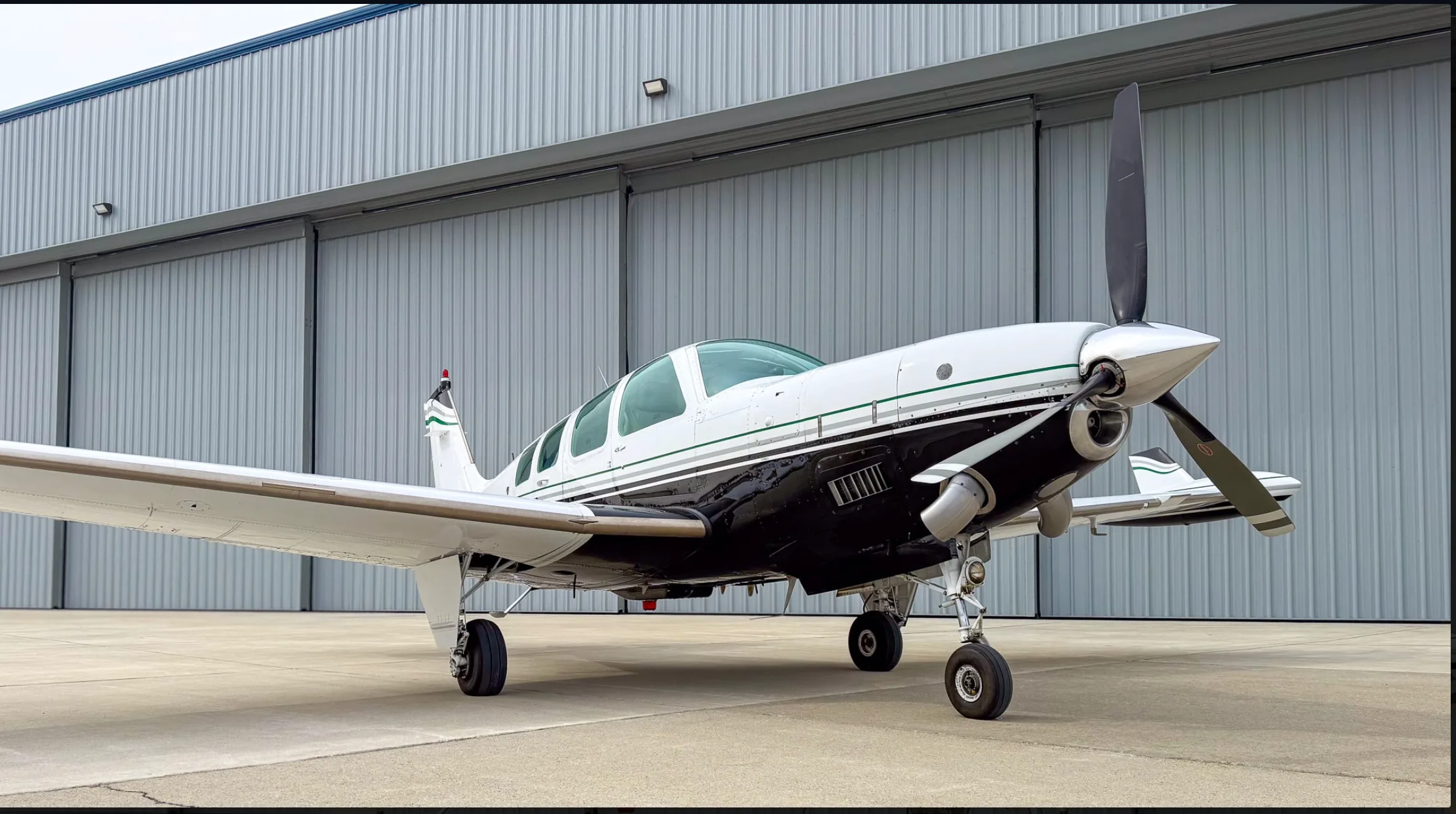 A low-angle front-side view of the white and black Beechcraft Baron N157BA, parked on an airfield.