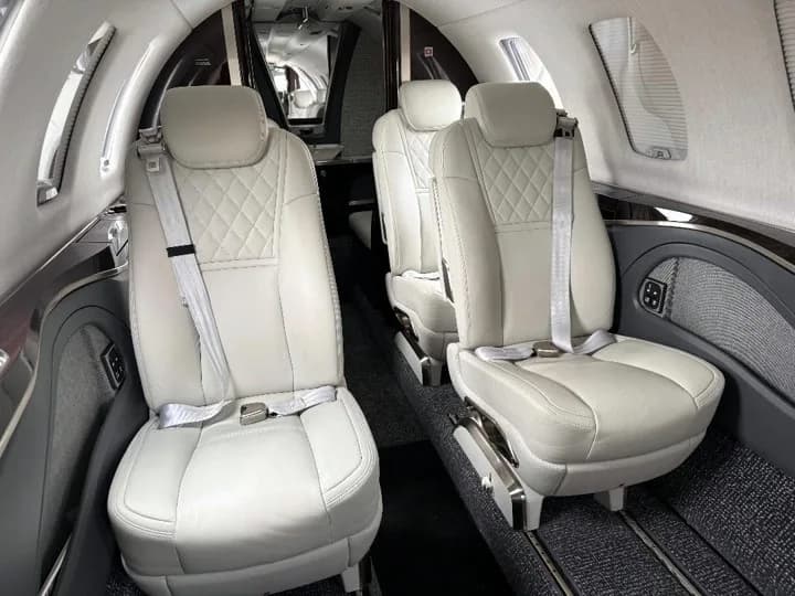 The aircraft's cabin interior with light-colored quilted leather seats and dark carpet.