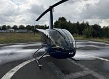 A blue Robinson R44 helicopter on a helipad, viewed from the front.
