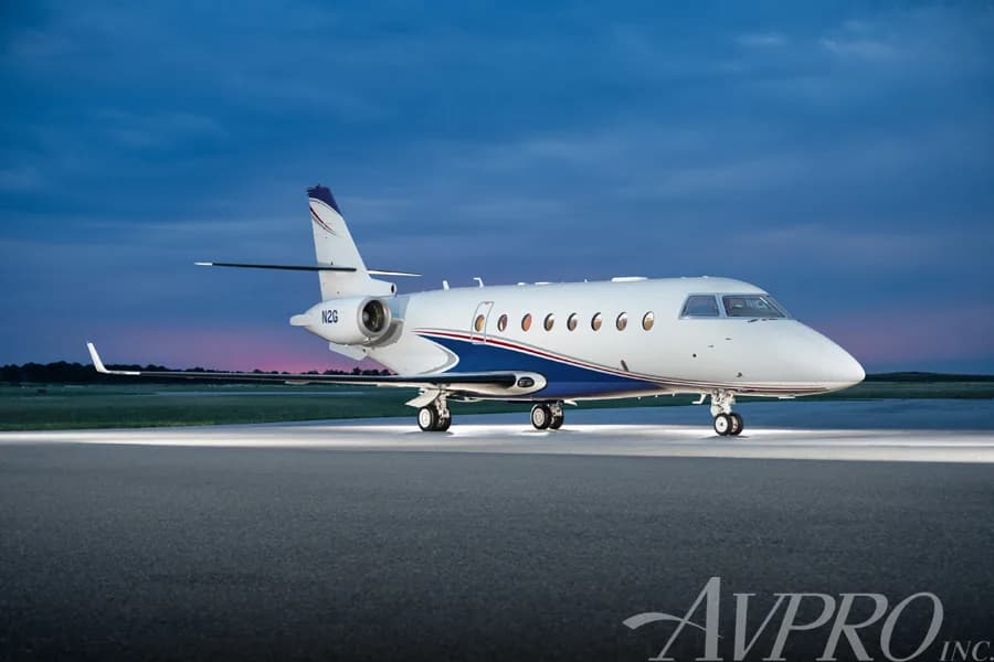 A Gulfstream G200 business jet, tail number N2G, parked on a tarmac at dusk with landing lights on.