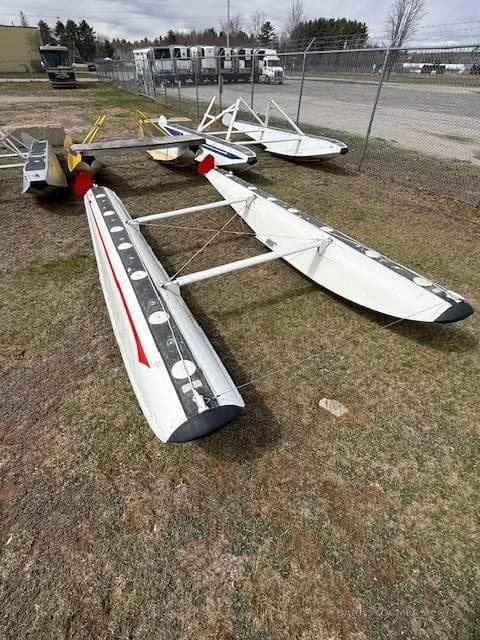 A pair of white aircraft floats with red stripes lying on the grass at an airfield.