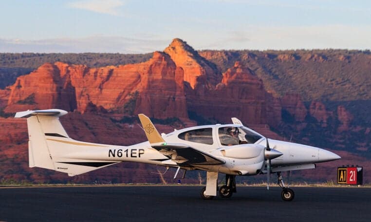 Diamond DA62 aircraft with tail number N61EP on the runway with a red rock mountain in the background.