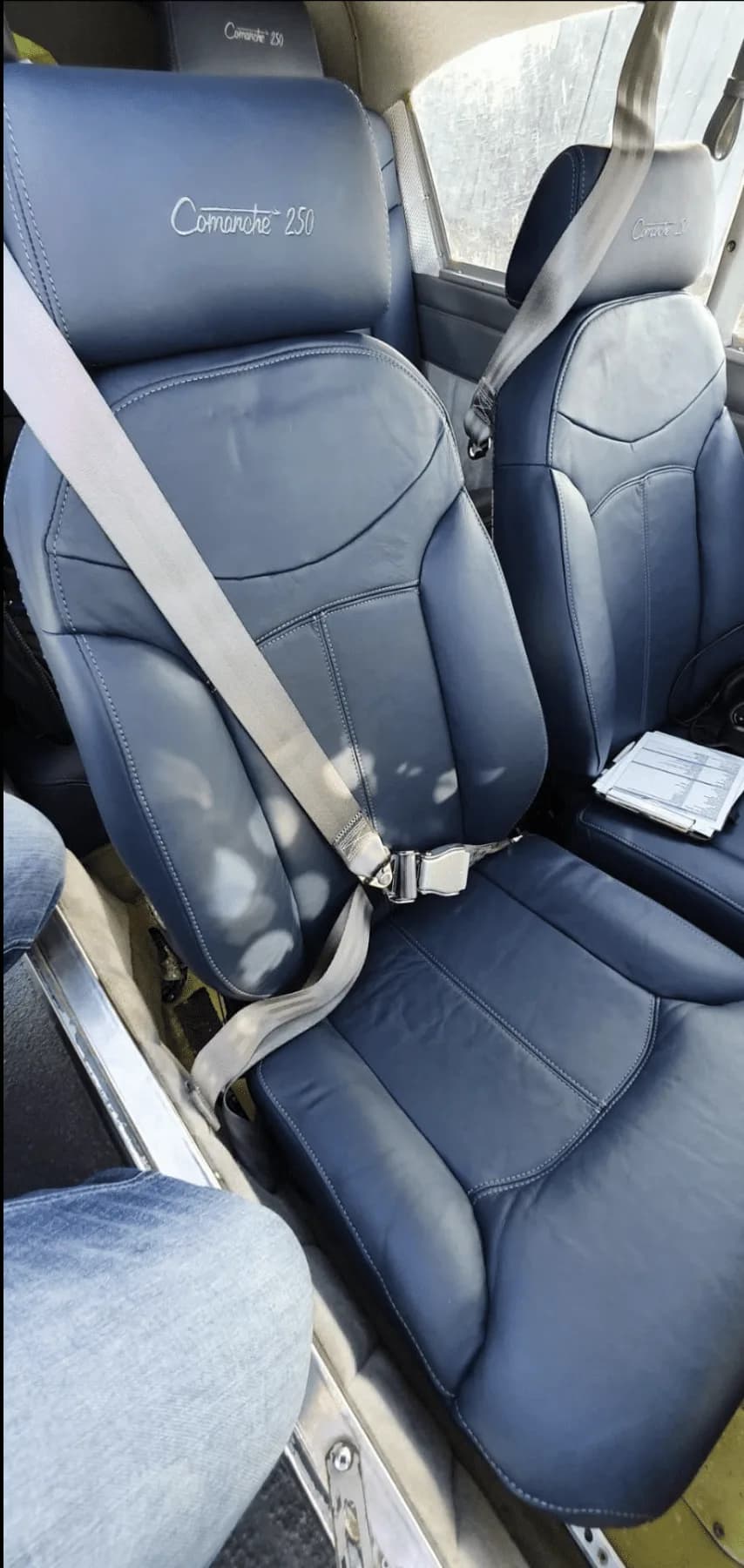 Front seats of a Piper Comanche 250 with blue leather upholstery.
