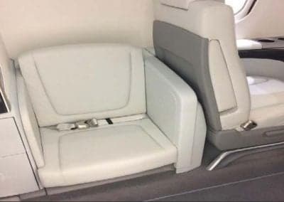 Close-up of the aircraft's white leather seats with seatbelts.