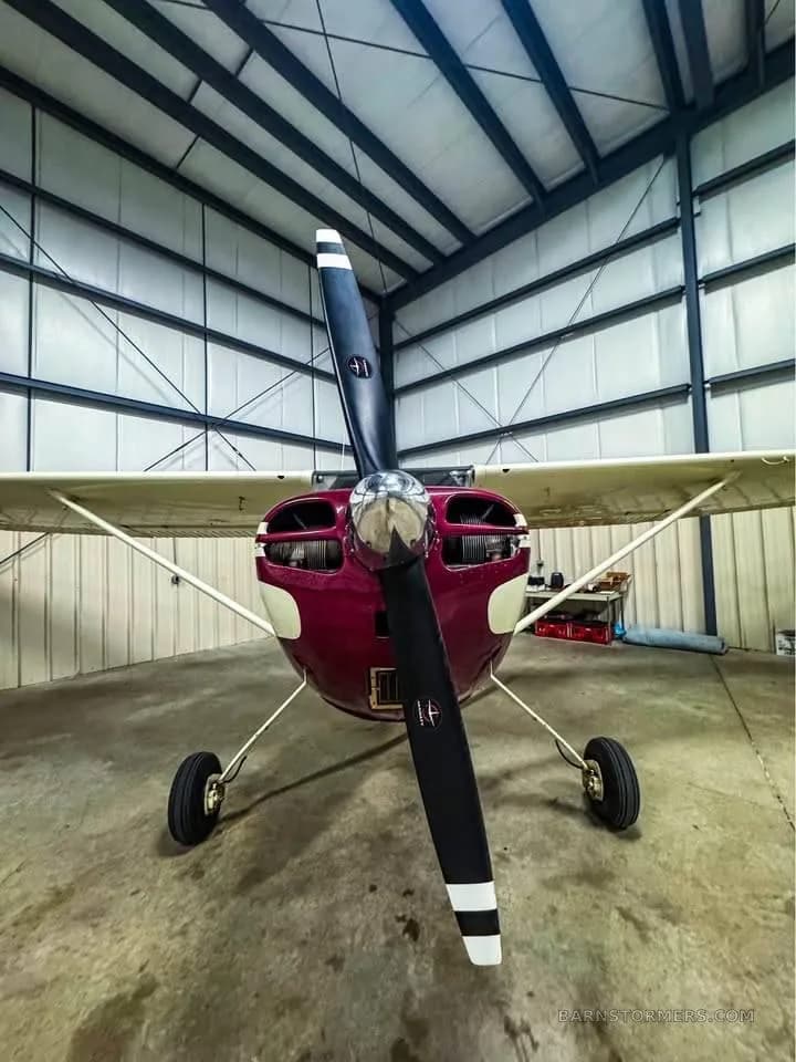 A head-on view of a red and white single-engine propeller aircraft with its propeller centered.