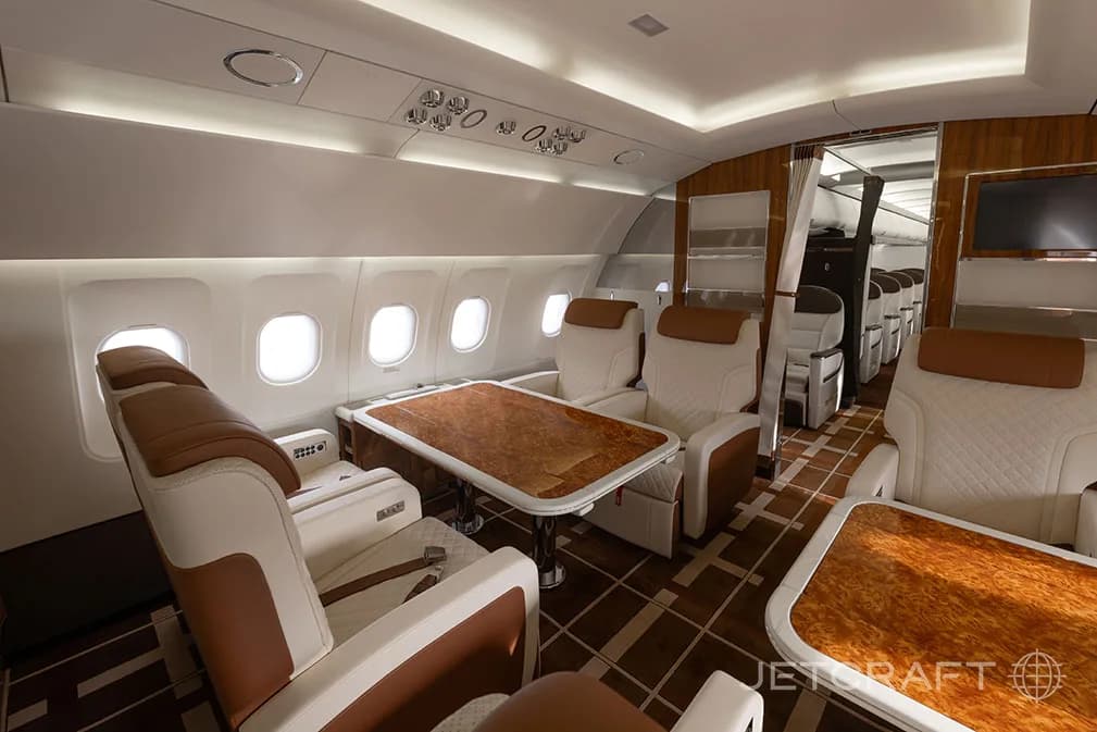 A luxurious aircraft cabin with individual seats and wooden tables, looking towards the rear.