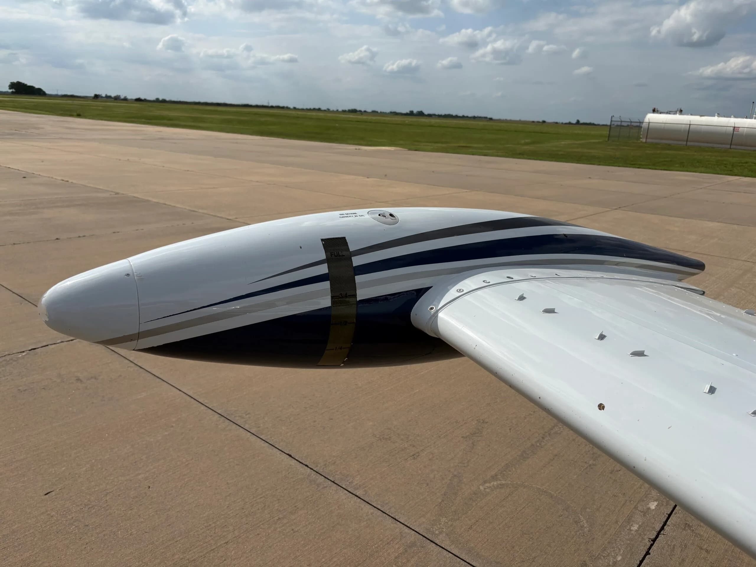 A close-up view of the wingtip and fuel tank of the white and blue Beechcraft Bonanza N686AG.