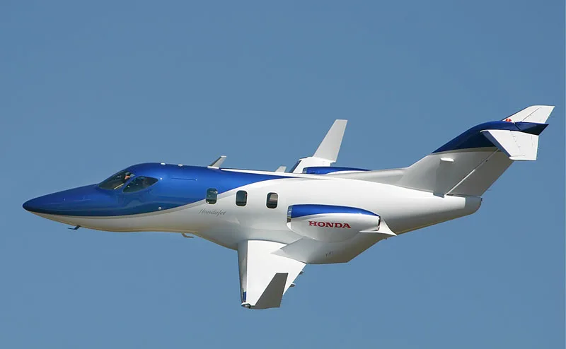 A blue and white HondaJet in flight.