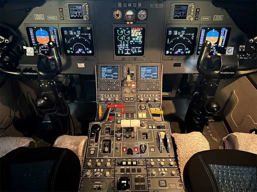 The advanced glass cockpit of a Gulfstream business jet, displaying multiple screens and control panels.