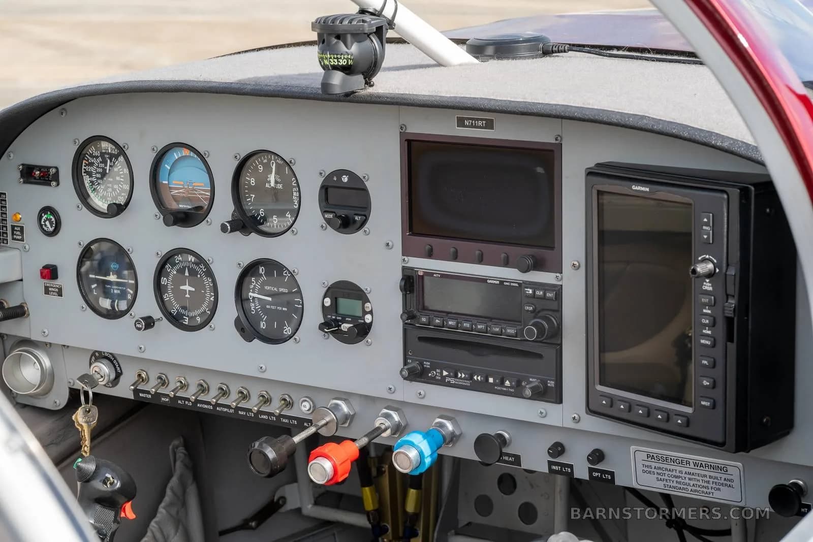 The cockpit instrument panel of the N711RT experimental aircraft, showing analog gauges and two digital displays.