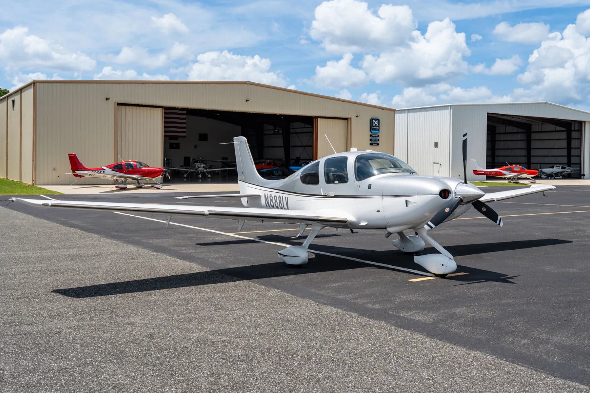 Three-quarter front view of a silver Cirrus SR22 aircraft (N888LV) parked on an airfield.