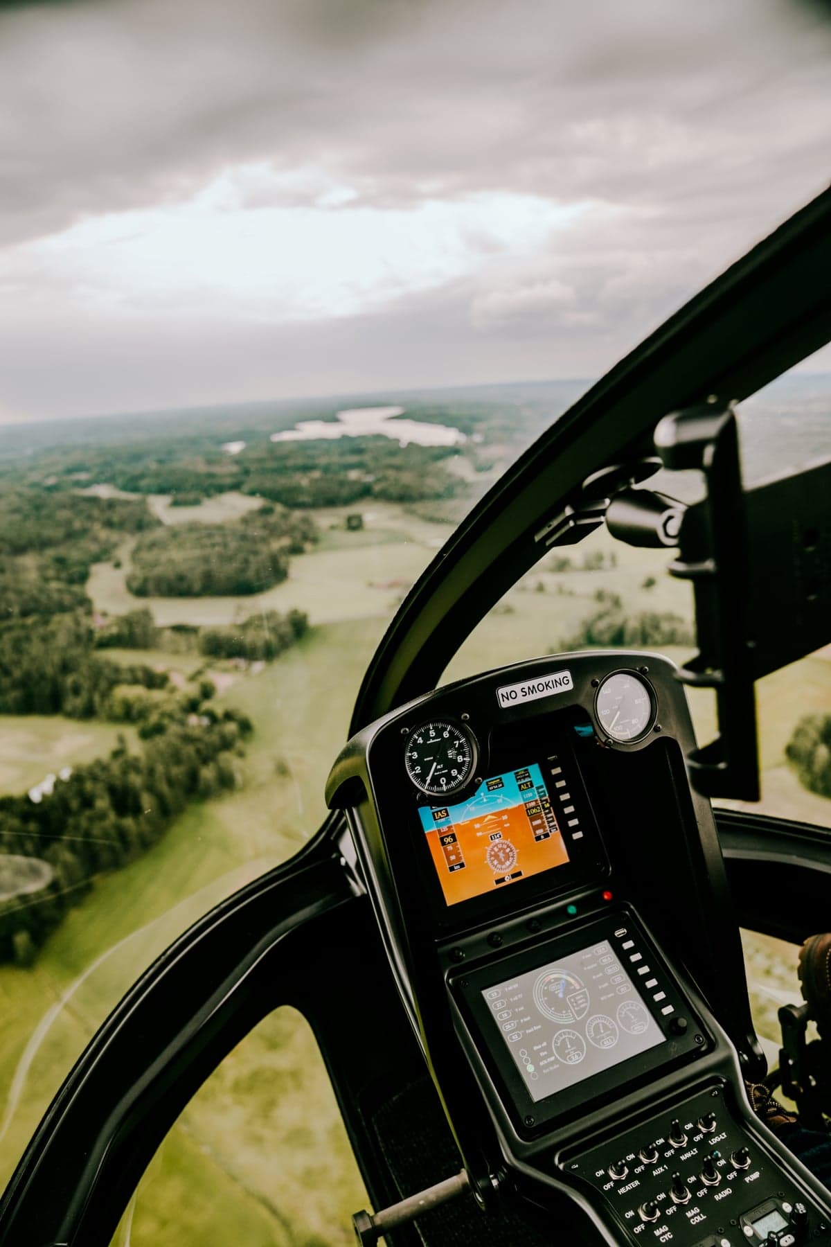 View of the helicopter cockpit in flight over a rural landscape.