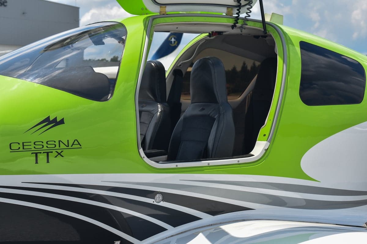 Front view of a green and black Cessna TTX with open doors.