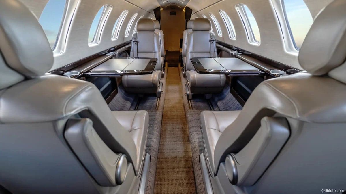 View of the aircraft's interior cabin with leather seats and fold-out tables.