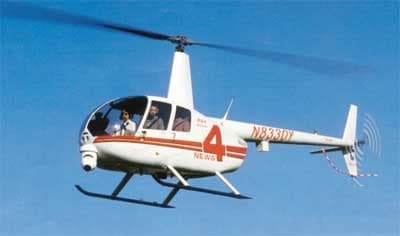 White Robinson R44 helicopter with red stripes in flight.