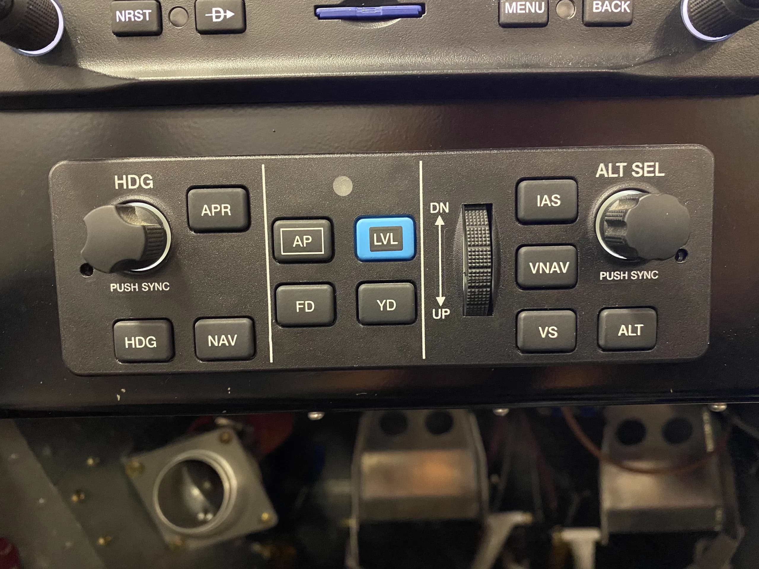 A close-up view of an aircraft autopilot control panel with buttons for HDG, APR, AP, FD, YD, LVL, IAS, VNAV, VS, and ALT.