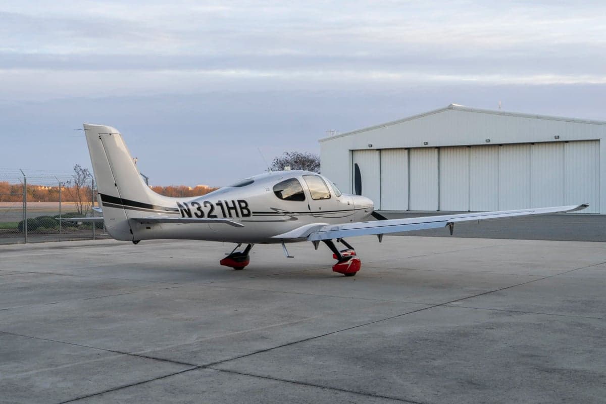 A Cirrus SR22T aircraft with a silver paint scheme parked on the tarmac.