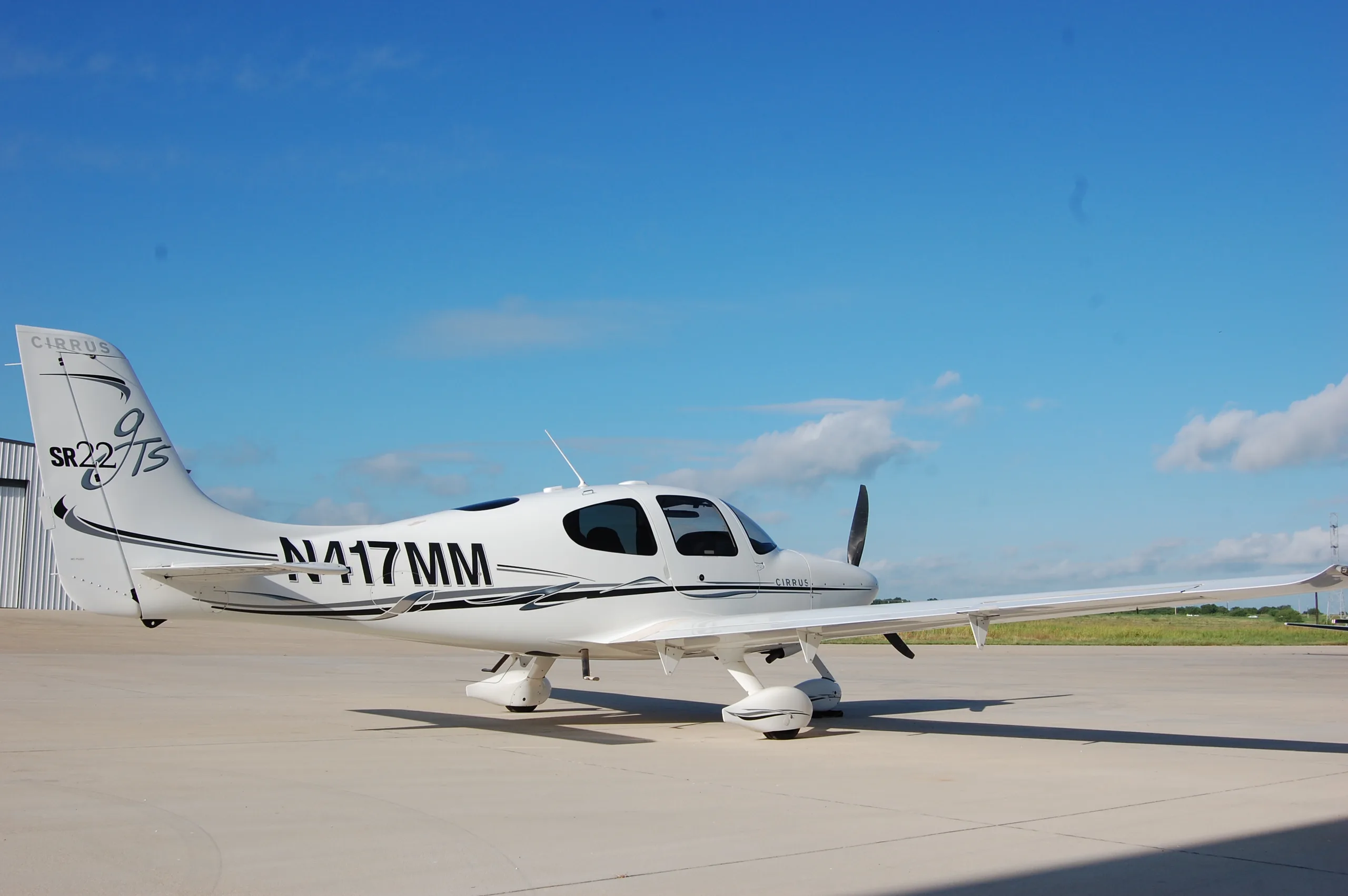 A three-quarter rear view of the white Cirrus SR22 aircraft, N417MM, parked on an airfield.