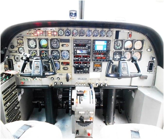 The cockpit features a complex instrument panel with analog gauges, digital displays, and two control yokes.