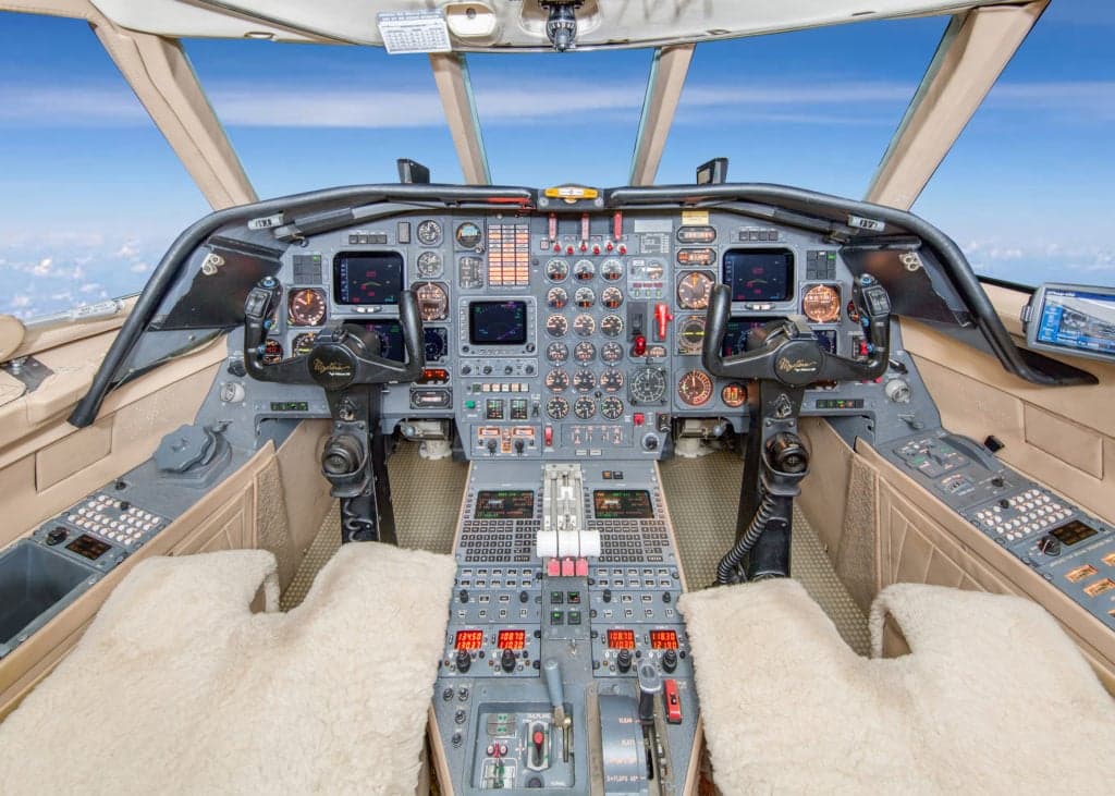 View of the interior cabin with cream-colored leather seats, wood trim, and a bar area.