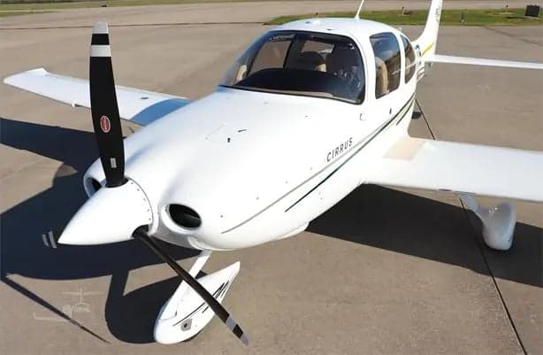 A Cirrus SR20 aircraft is parked on the tarmac.