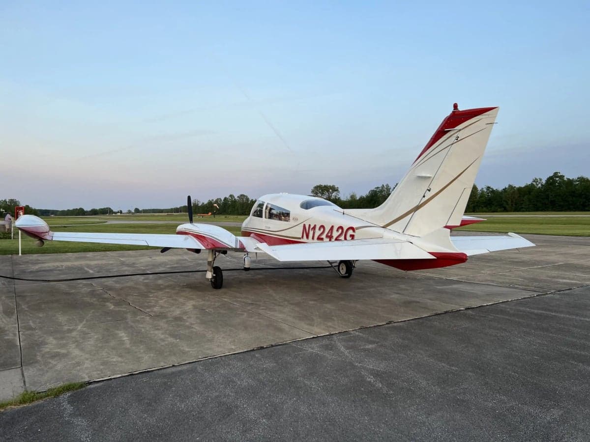 A white and red twin-engine aircraft, N1242G, parked on an airfield at dusk.