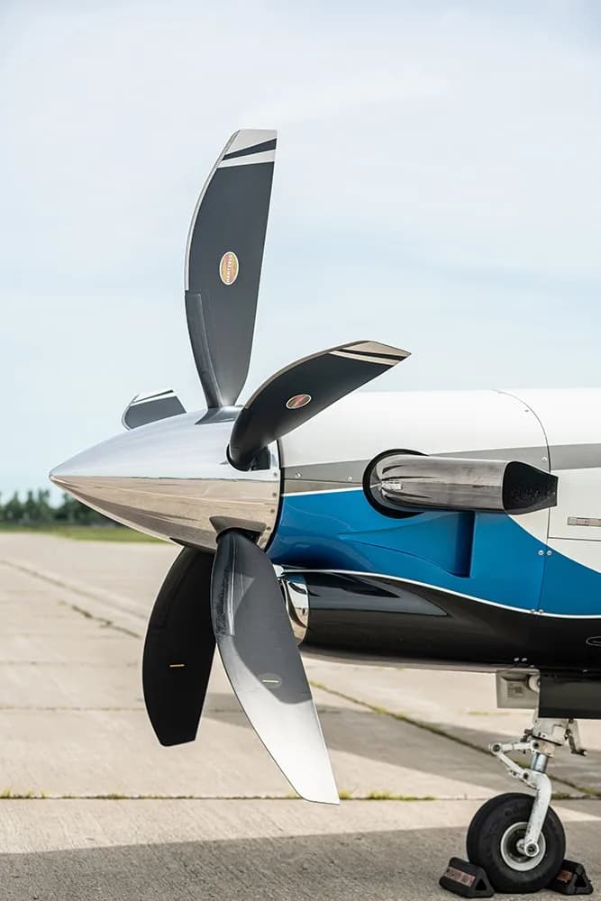 A close-up of the TBM 960 aircraft's propeller and engine cowling with a blue and black paint scheme.