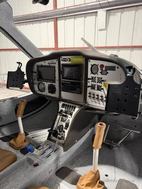 The cockpit of a light sport aircraft, showing the instrument panel with screens and controls, and two joysticks.