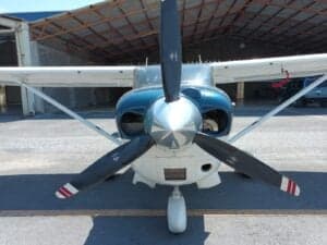 Close-up of the propeller and front of a Cessna aircraft with blue and white paint scheme.