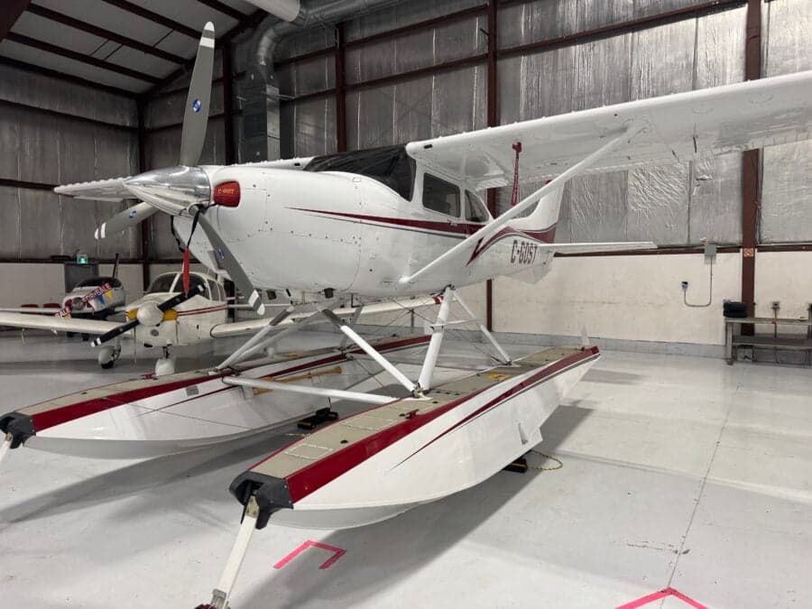 A Cessna 206 on floats is parked in a hangar.
